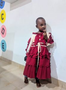 Maryam Kibwana, a young girl in a red dress, standing confidently